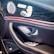 The image features the interior door panel of a luxury car, showcasing a sleek and modern design. It includes an elegant combination of materials such as leather and wood grain finish. Visible elements include a high-quality speaker with chrome accents, seat adjustment buttons, and a window control panel.