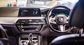 A sleek car interior showcasing the dashboard and steering wheel, featuring a digital display with the message 'Welcome, BMW driver 1'. The interior design is modern with black and silver accents.