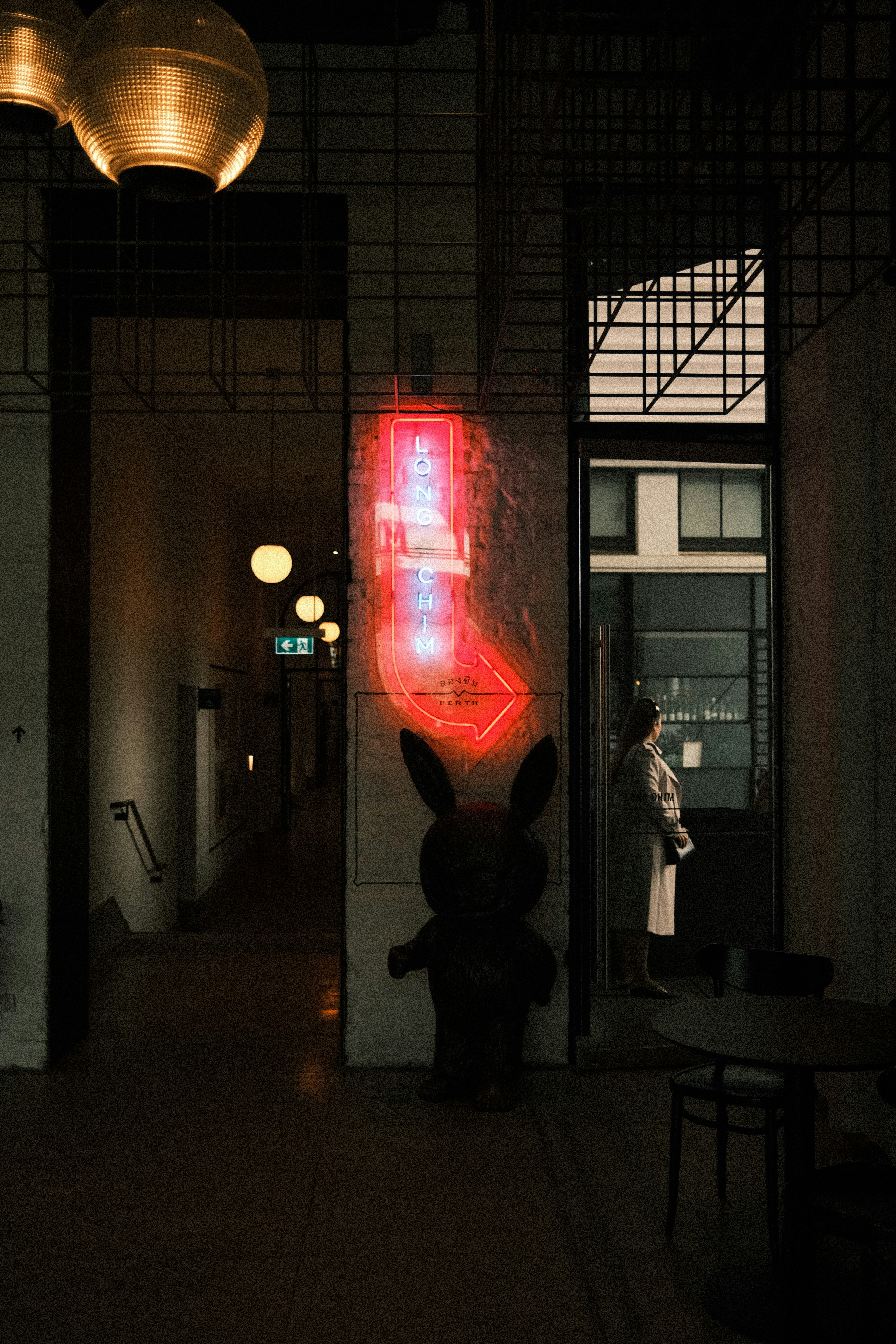 a person standing in a dark hallway next to a red light