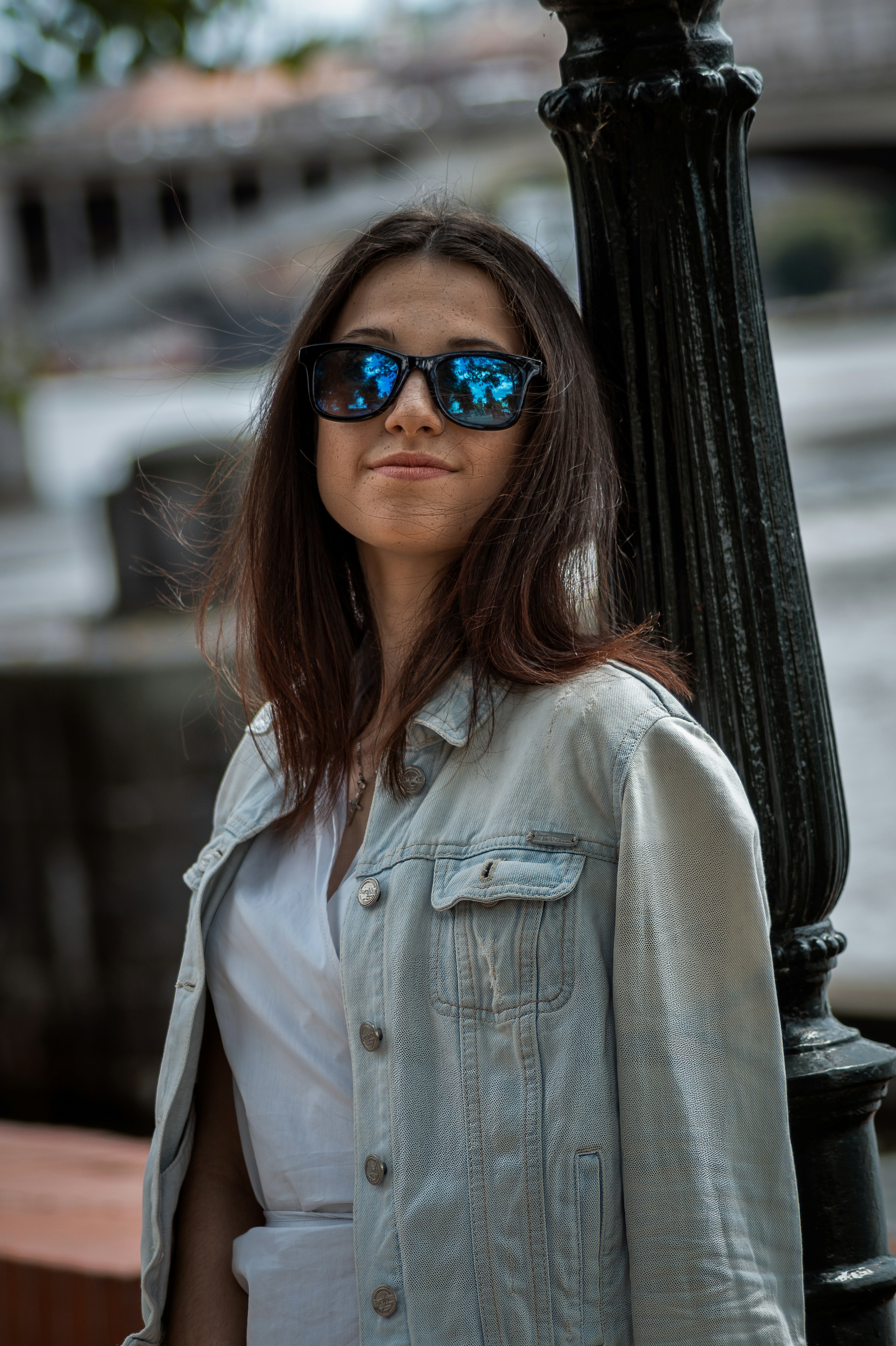 a woman wearing sunglasses standing next to a lamp post