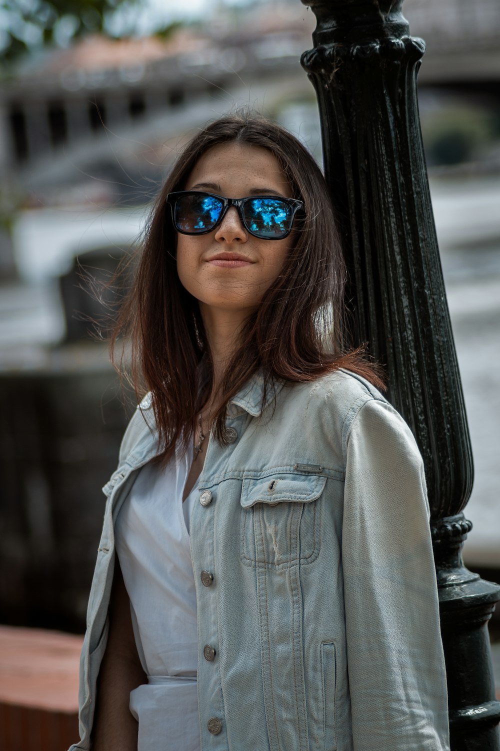 a woman wearing sunglasses standing next to a lamp post