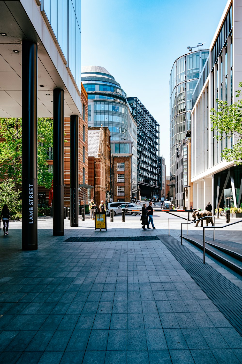 a couple of people walking down a street next to tall buildings