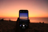 Sunset view of a traveler capturing photos with phone connected via VietLynk SIM on a beach.