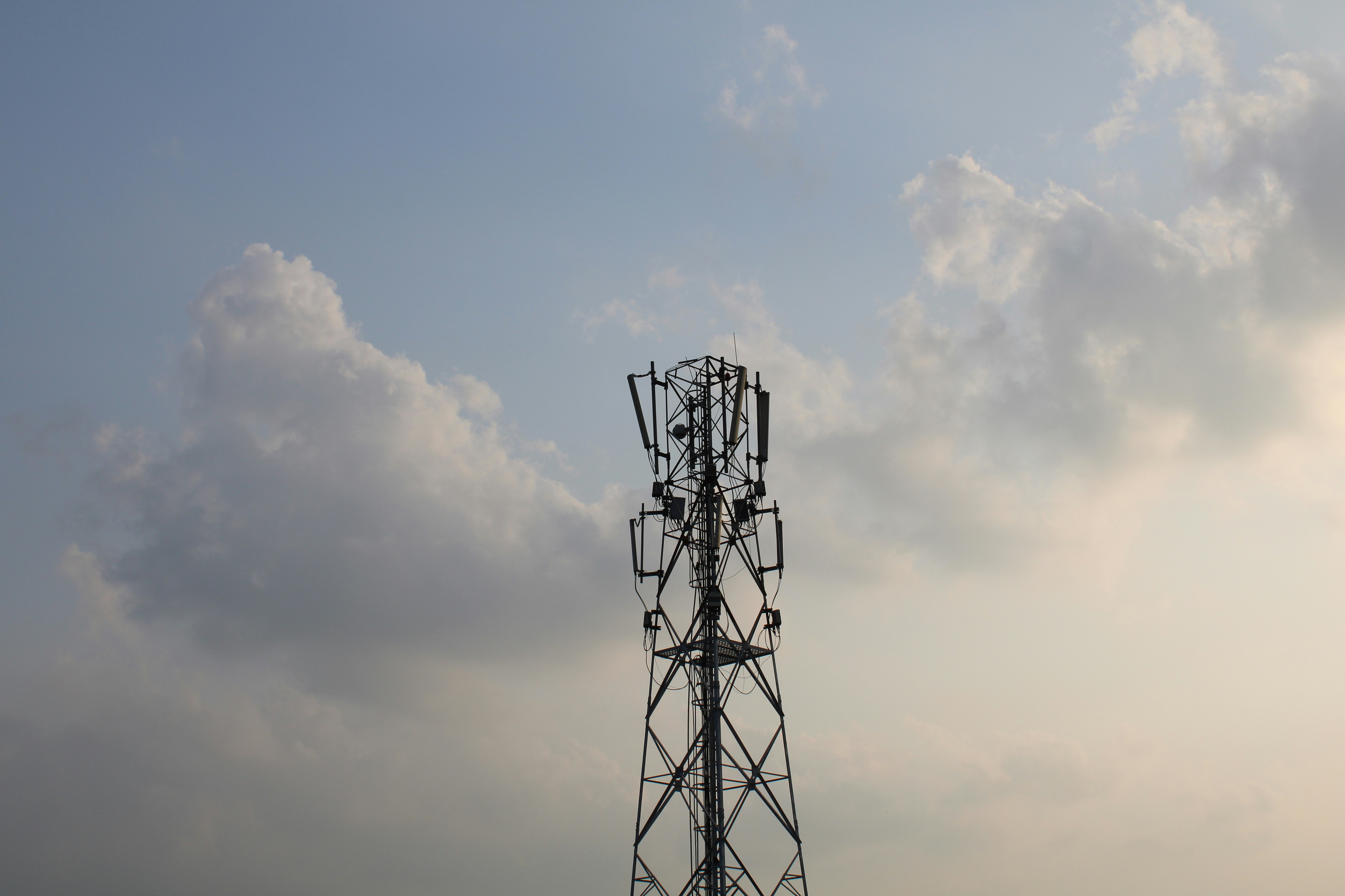 Telecommunication tower at dusk against dark sky, dramatic low-key lighting