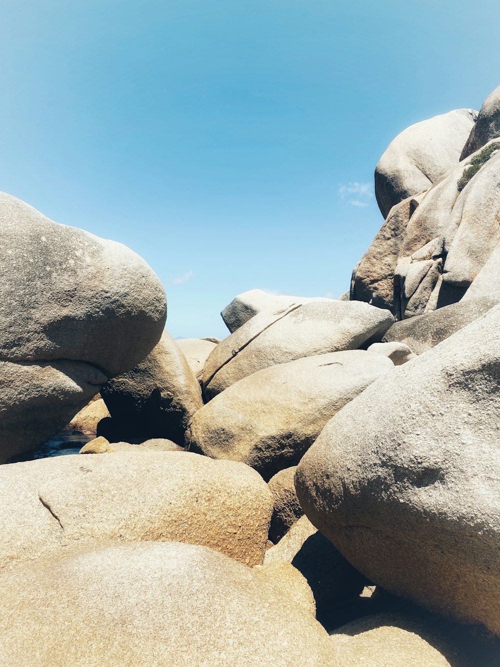 a rocky beach with large rocks and a clear blue sky