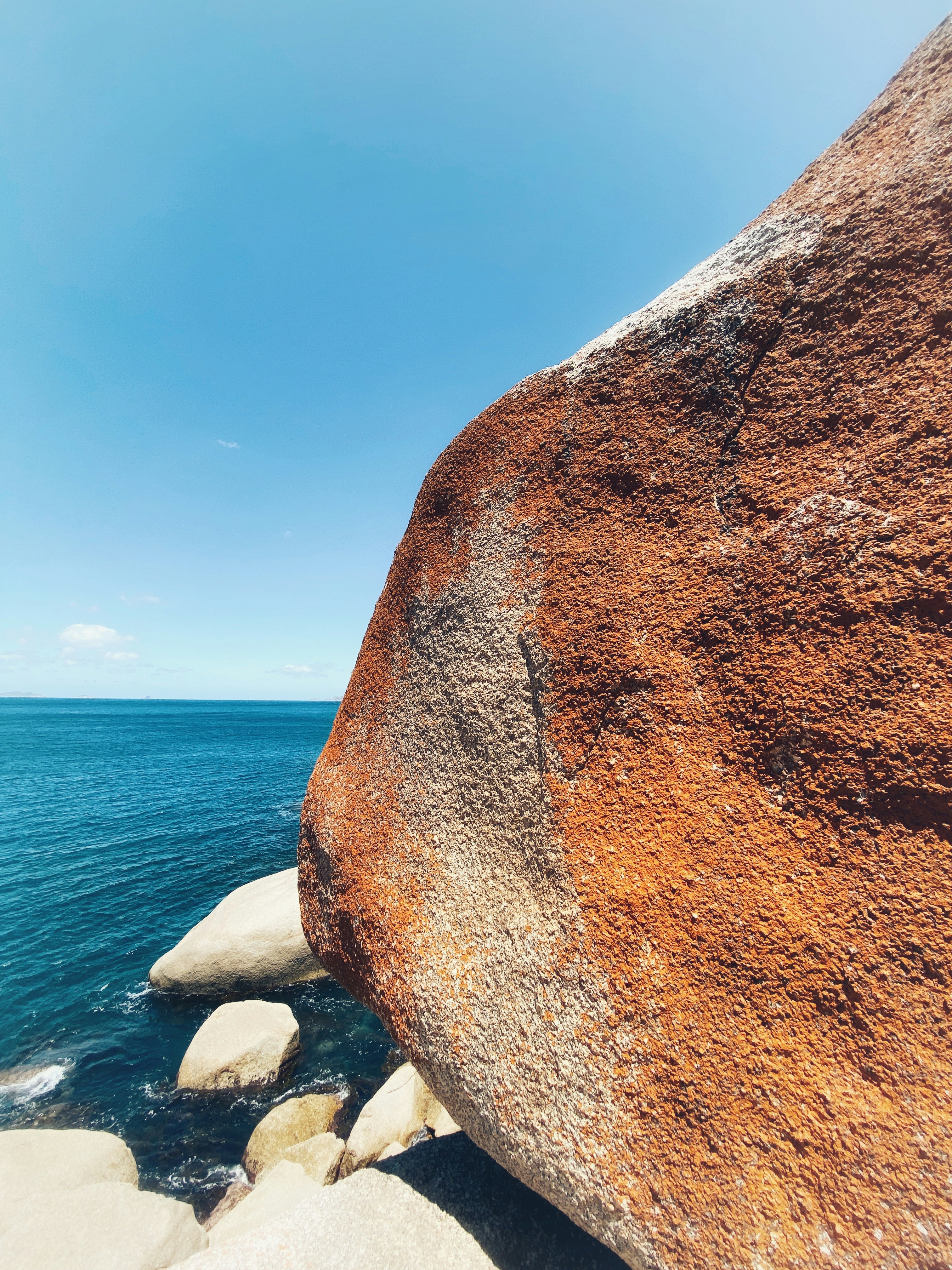 A large rock sitting on top of a beach next to the ocean photo – Free ...