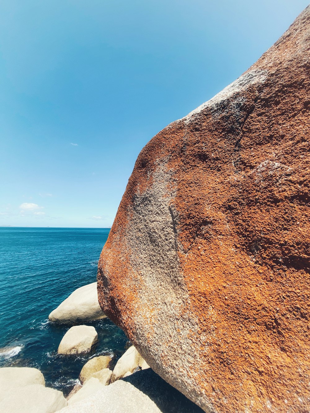 a large rock sitting on top of a beach next to the ocean