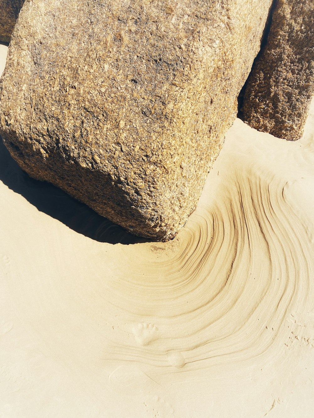 a large rock sitting on top of a sandy beach