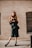 a woman in a black dress is standing on a sidewalk
