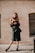 a woman in a black dress is standing on a sidewalk
