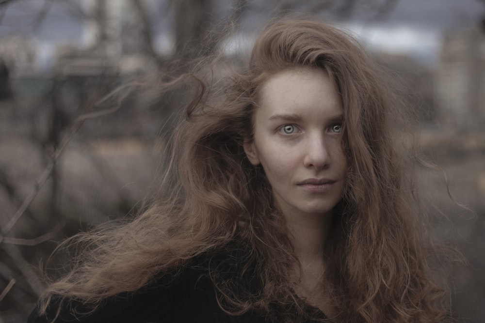 a woman with long hair standing in the woods