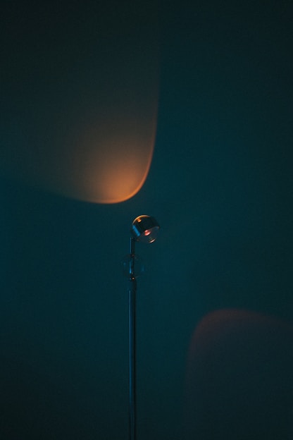 A sleek smart lamp casting flowing amber-indigo gradients against a dark midnight backdrop.