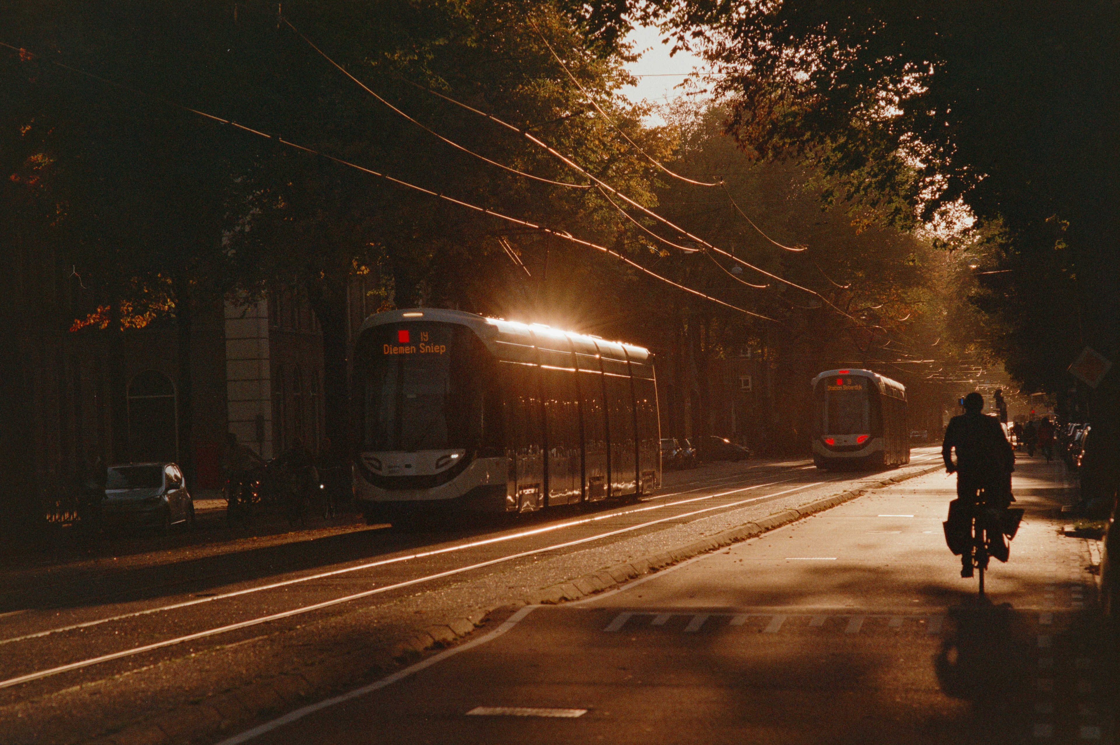 a person riding a bike down a street next to a train