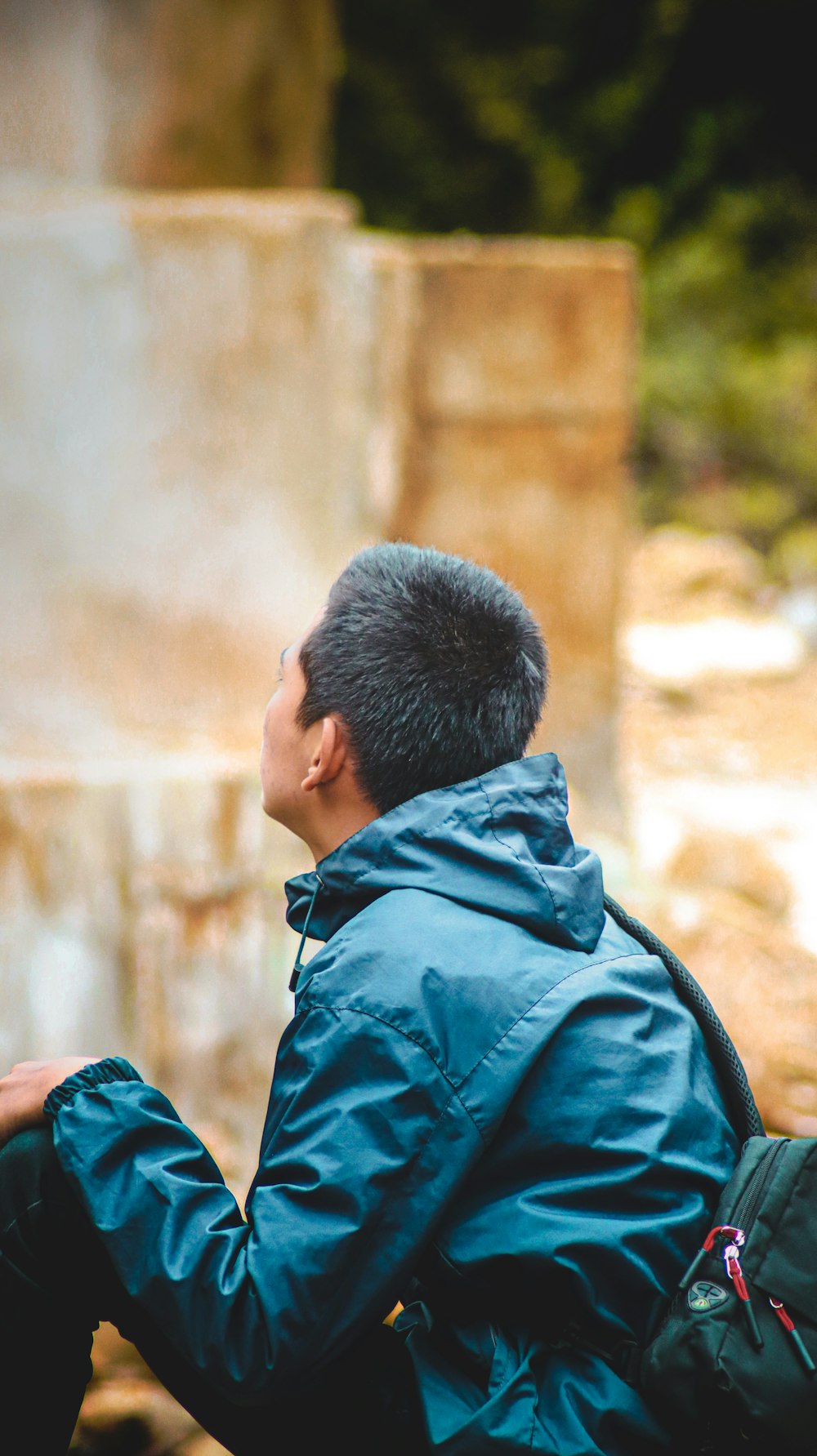 a man in a blue jacket sitting on a rock