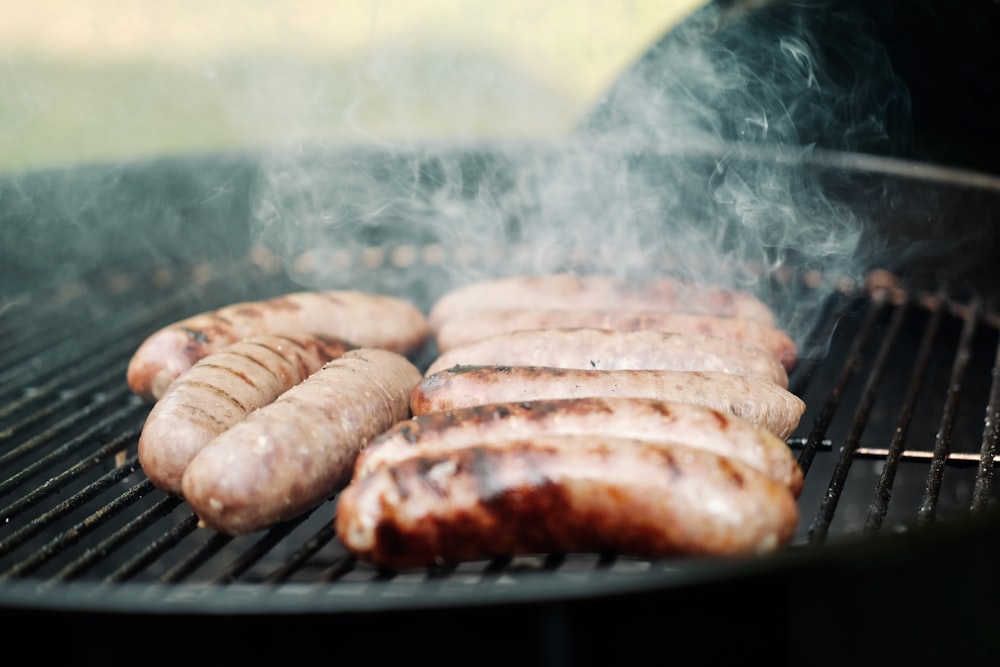 hot dogs and sausages cooking on a grill