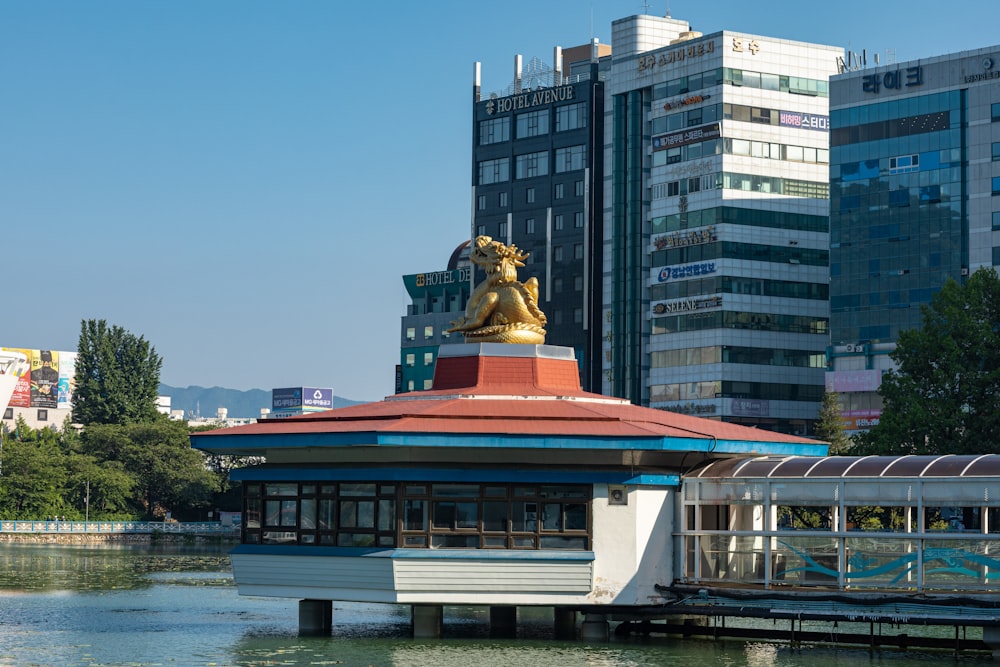 a building with a statue on top of it next to a body of water