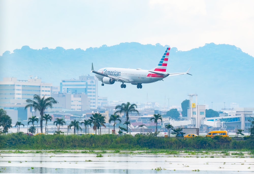 a large jetliner flying over a lush green hillside