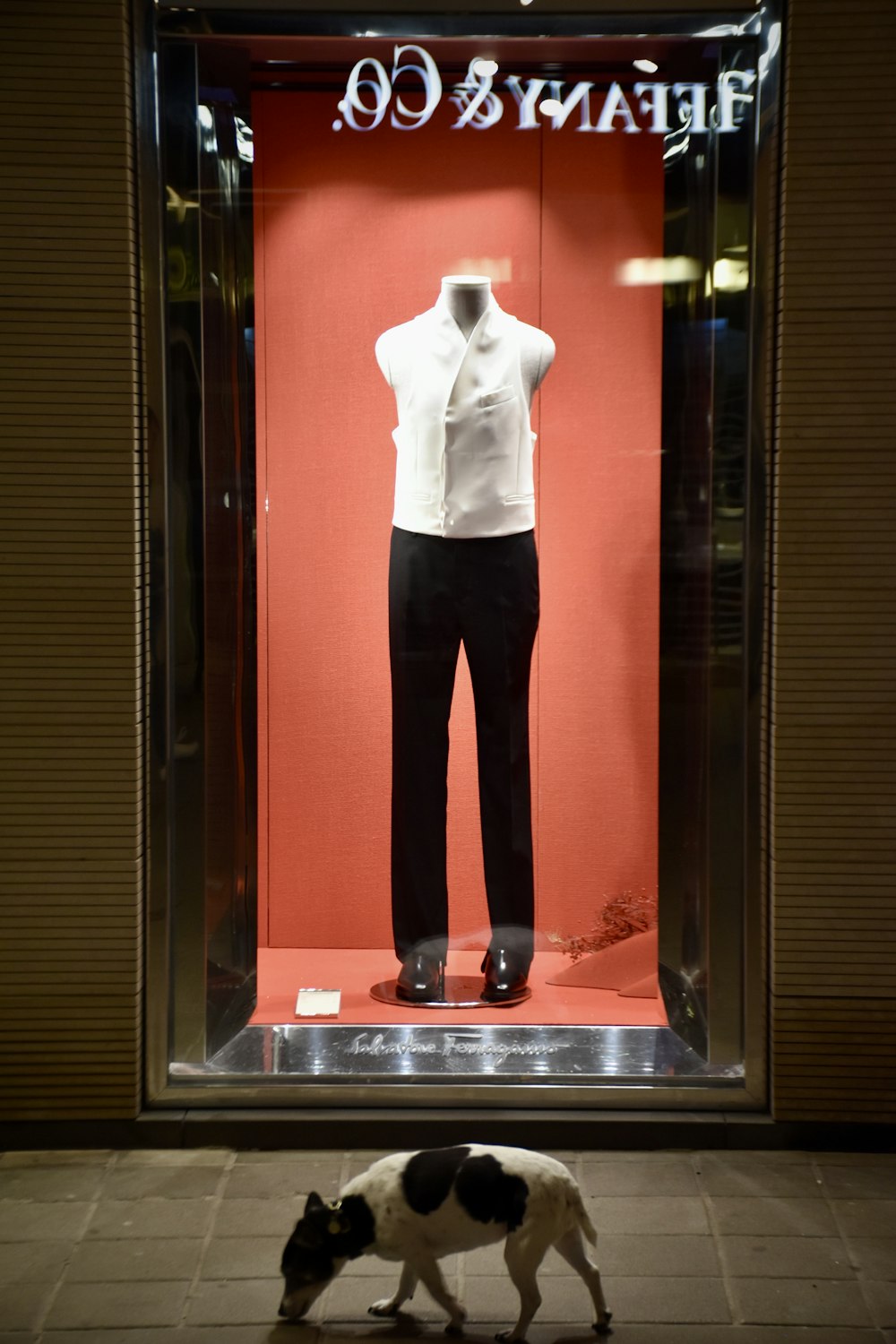una vetrina con un manichino vestito con una camicia bianca e pantaloni neri