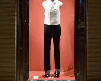 a display case with a mannequin dressed in a white shirt and black pants