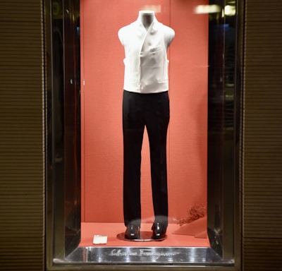 a display case with a mannequin dressed in a white shirt and black pants