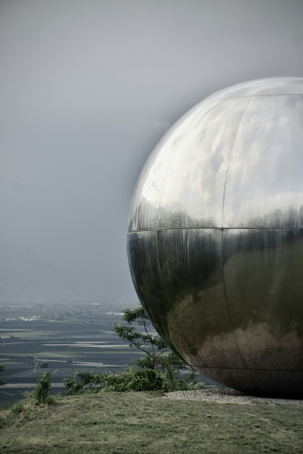 a large metal object sitting on top of a lush green field