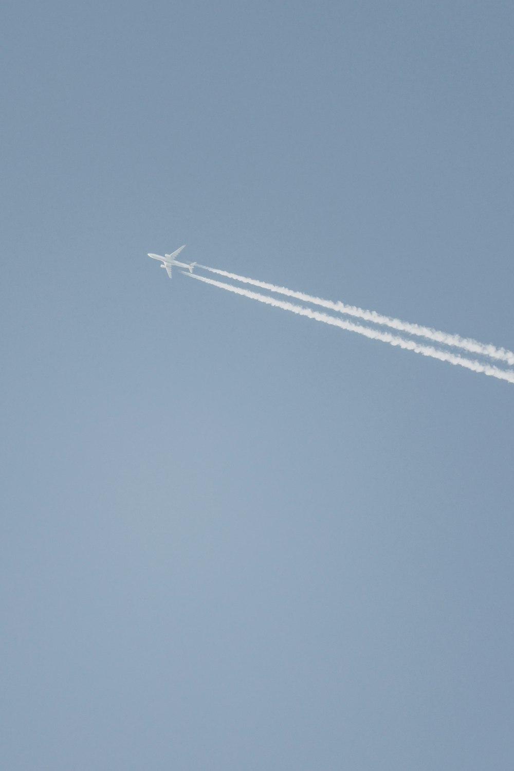 an airplane flying in the sky leaving a trail of smoke