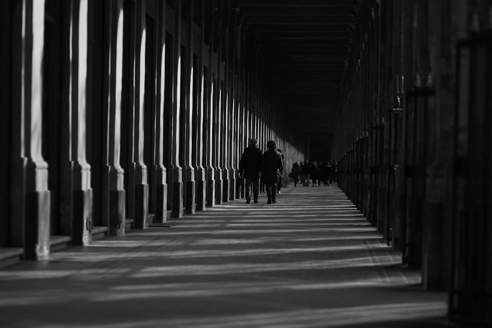 a black and white photo of people walking down a hallway