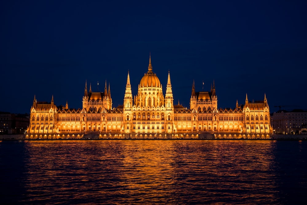 a large building lit up at night by the water