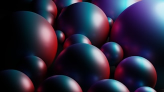 Abstract image of multiple spheres in various sizes with a shiny, reflective surface. The colors on the spheres fluctuate between dark blue, purple, and hints of red hues, creating a futuristic and polished look.