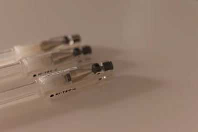 Close-up of smooth, fine-tip pens resting on a light gray textured surface.