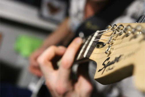 Close-up of hands tuning a guitar, symbolizing dedication and craft.