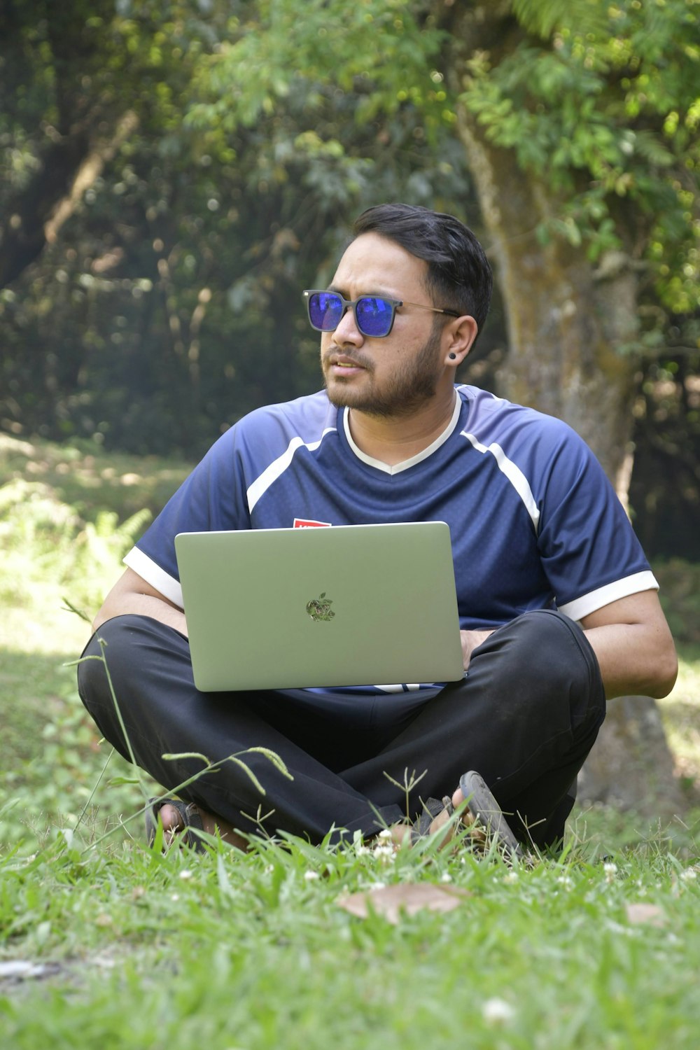 a man sitting in the grass with a laptop