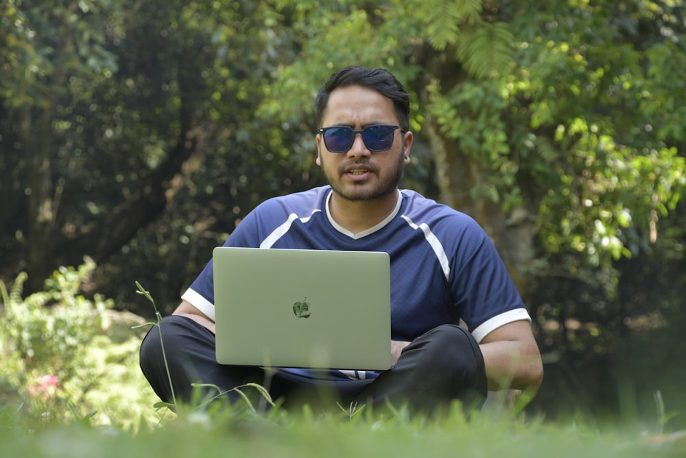a man sitting in the grass with a laptop