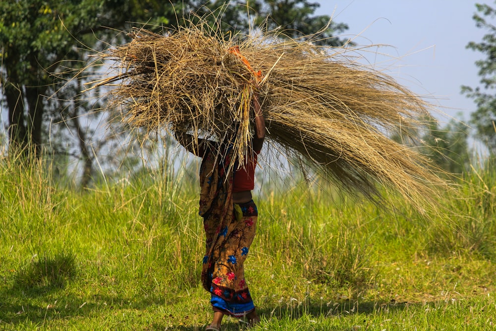 a woman carrying a bundle of hay on her back