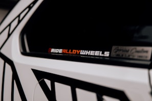 Sporty alloy wheels and a set of custom car decals displayed on a garage wall.