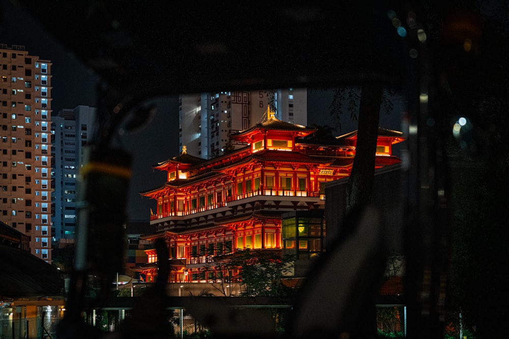 a building lit up at night with buildings in the background