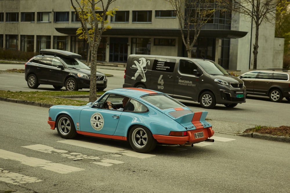 a blue and orange car driving down a street