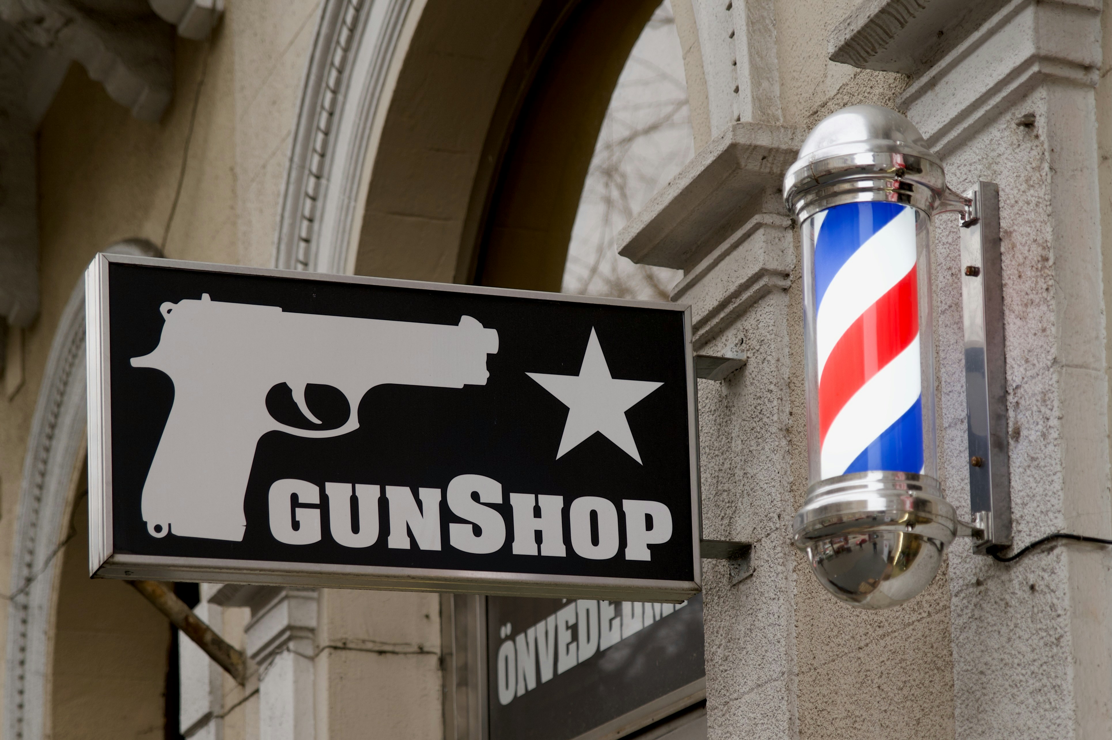 a sign that says gunshop with a gun hanging from the side of a building