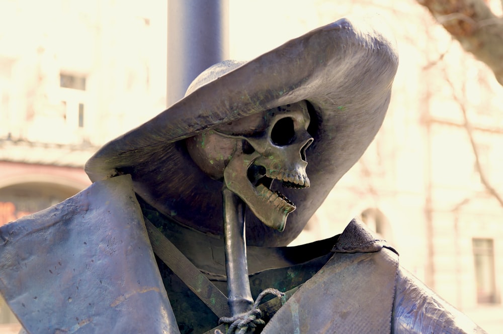 uma estátua de um esqueleto usando um chapéu e segurando um cachimbo