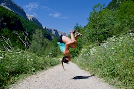 a woman doing a handstand on a dirt road
