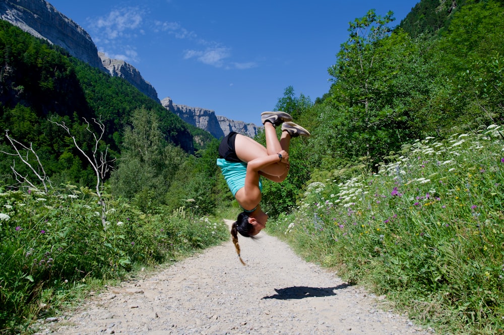 a woman doing a handstand on a dirt road