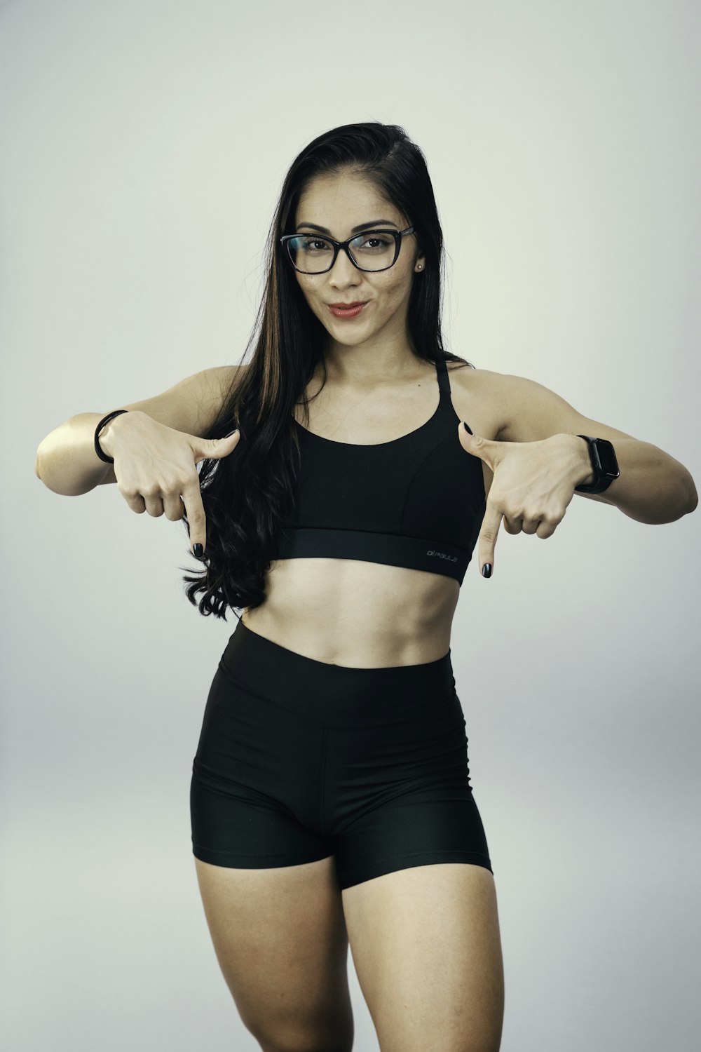 a woman in a black sports bra top pointing at the camera