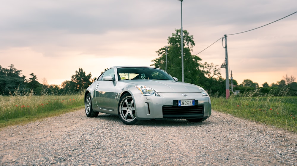 a silver sports car parked on a gravel road