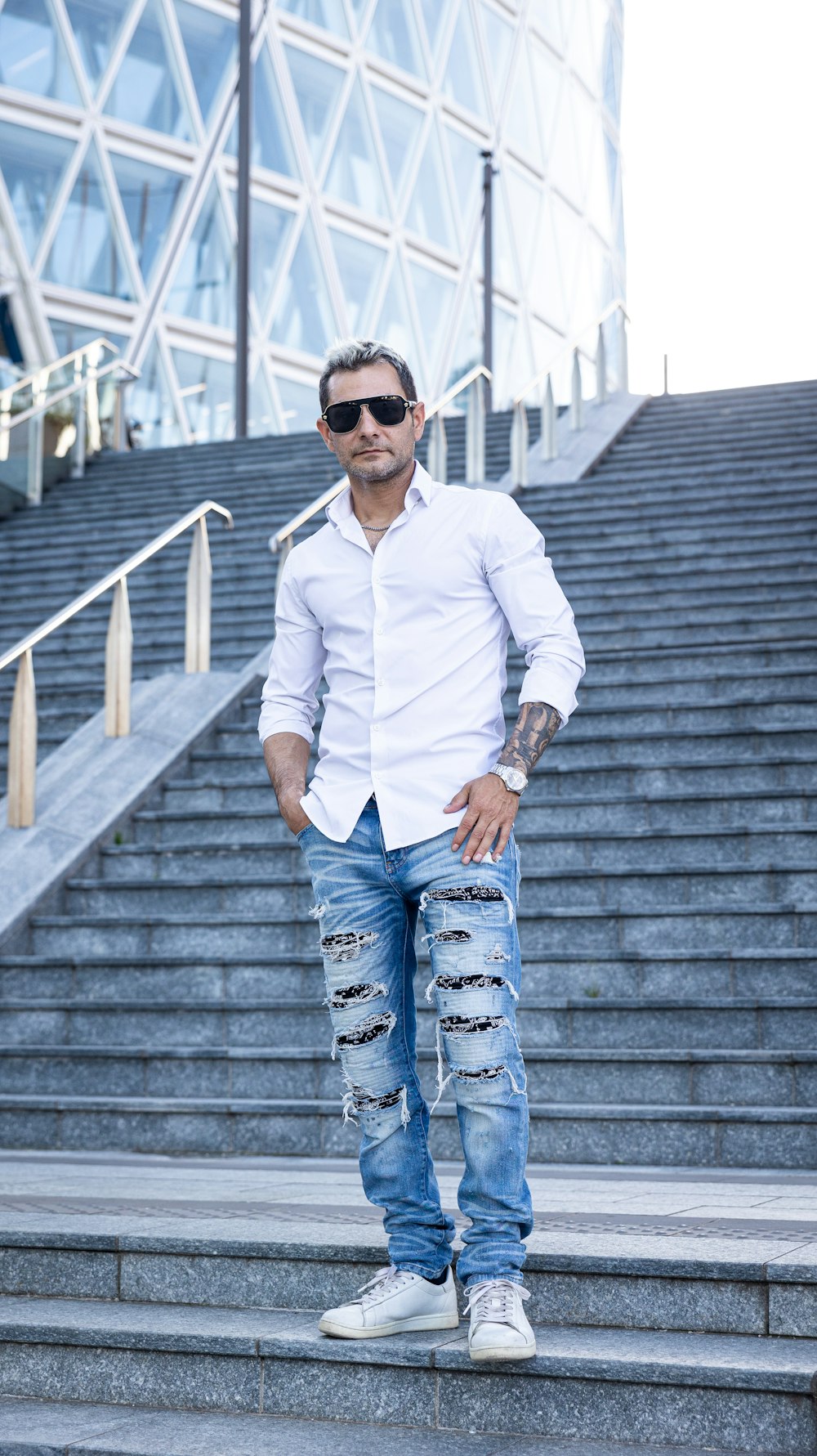 a man standing on a set of stairs with his hands in his pockets