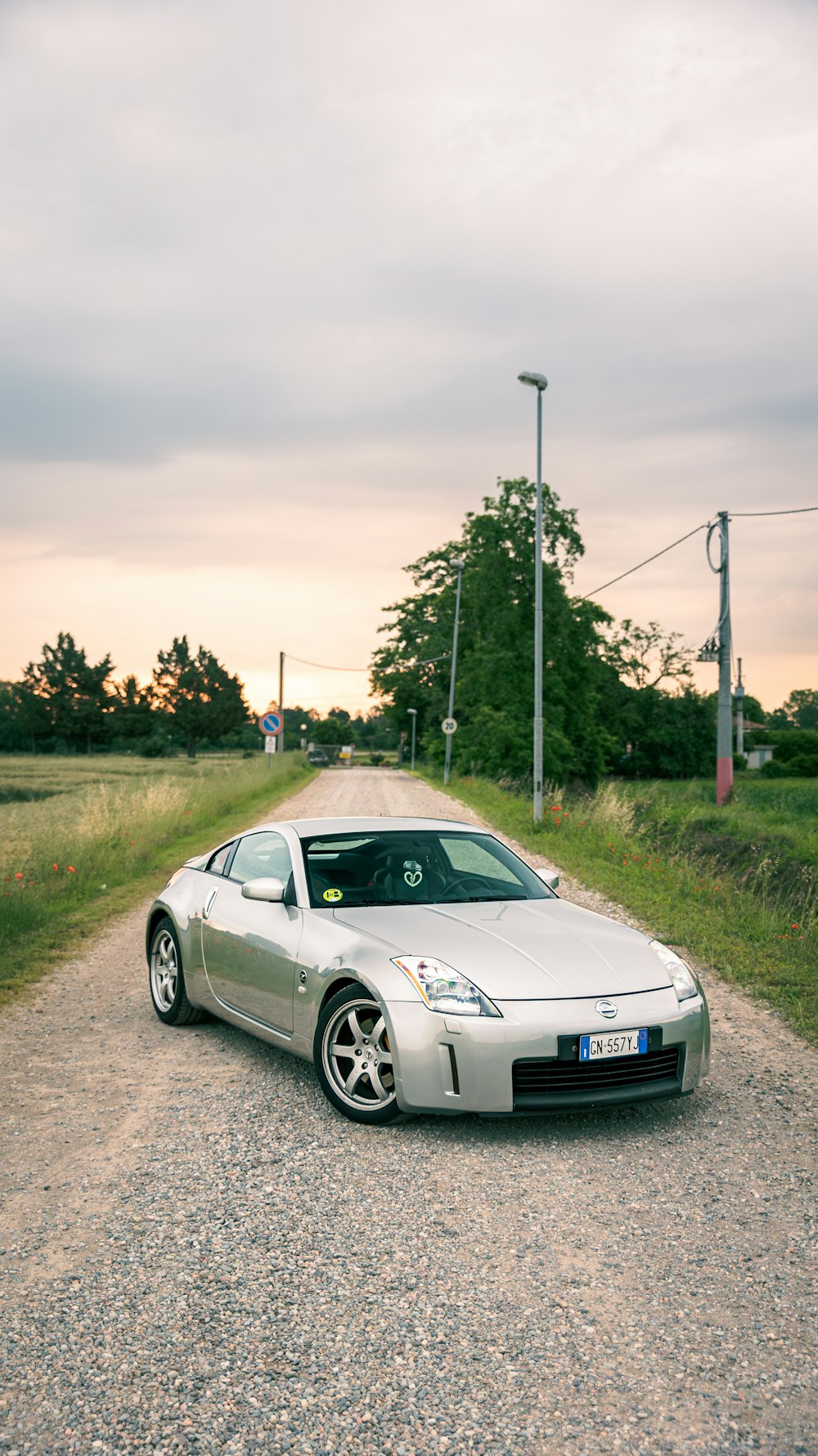 a silver sports car parked on a gravel road