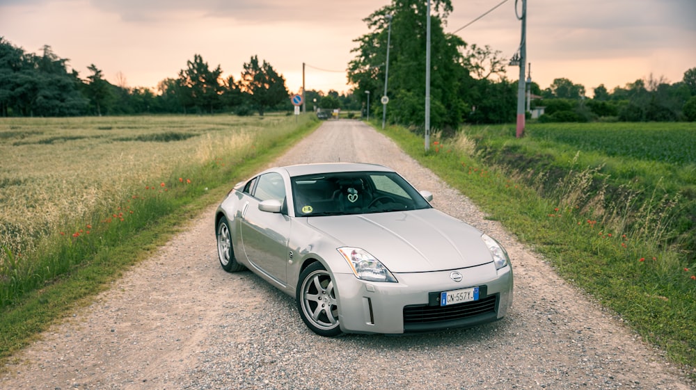 a silver sports car parked on a gravel road