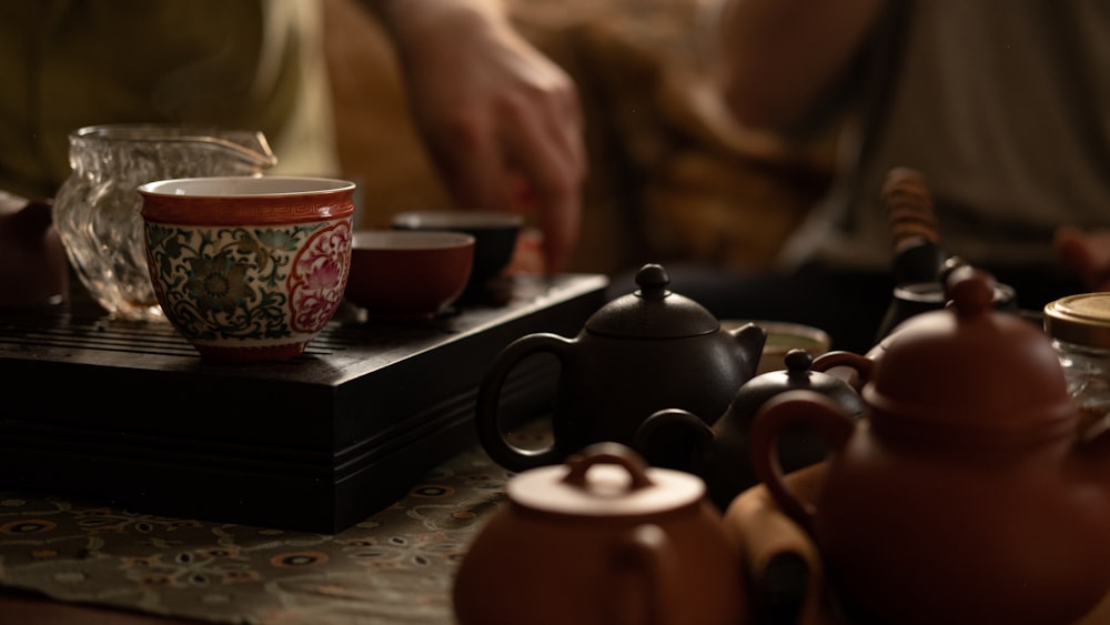 a table topped with tea cups and tea kettles