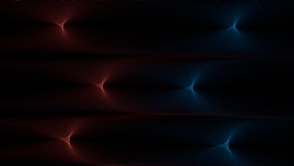 A digital artwork featuring symmetrical, glowing patterns resembling starbursts. The left side displays red hues while the right side shifts to blue, set against a dark background.