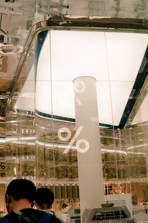 A sleek, minimalist workspace featuring a transparent glass card displaying loan rates, set against modern US architecture with diverse professionals collaborating nearby.