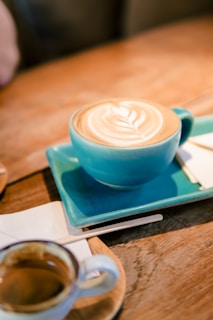 Close-up of a beautifully crafted specialty coffee cup on a wooden table with a soft blue napkin.